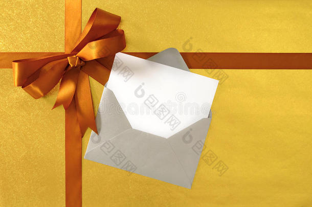 圣诞或生日卡，金色礼品丝带和蝴蝶结在纸背景，空白问候卡和信封