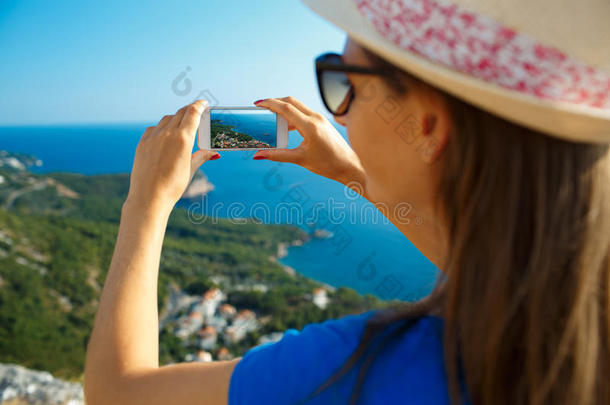 戴帽子的女孩用智能手机制作照片，风景如画