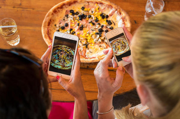 朋友们用智能手机拍披萨的照片