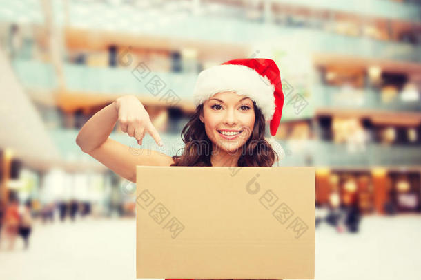 微笑的女人戴着圣诞老人的帽子，拿着包裹盒