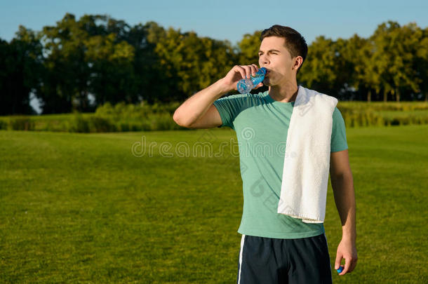 漂亮的运动员在草坪上喝水。