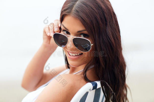 微笑的年轻女子在海滩的休息室里晒日光浴
