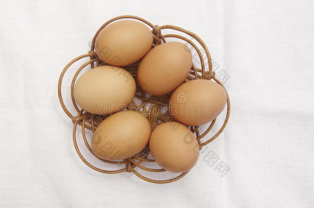 棕色鸡蛋在柳条篮子上，白色桌布背景