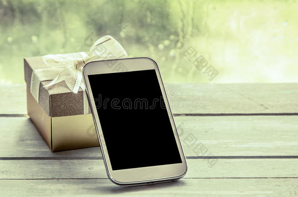 手机，智能手机，木制桌子上有礼品盒的手机