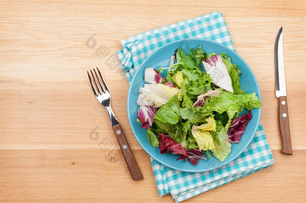 盘子里有新鲜沙拉，刀叉。减肥食品