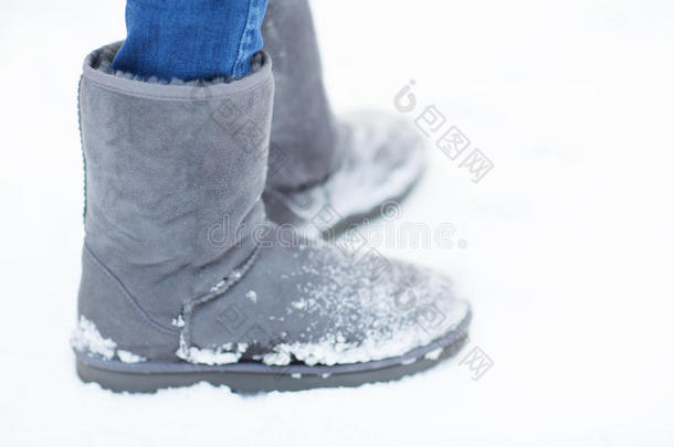 靠近女人的腿，穿着温暖的靴子在雪地上