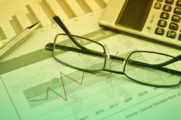 金融图表和图表上的眼镜、钢笔和计算器