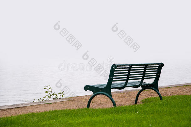空荡荡的公园长凳，从雾蒙蒙的湖岸上的雨中<strong>湿透</strong>了