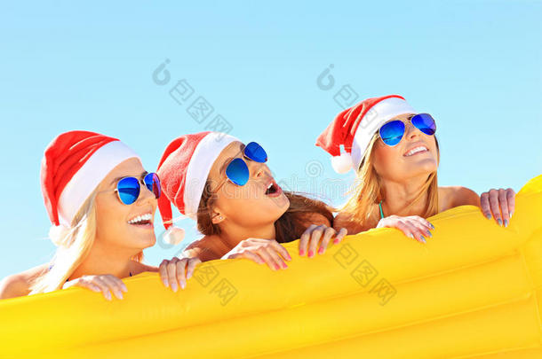 <strong>一群</strong>戴着圣诞<strong>老人</strong>帽子的女孩在海滩上玩得很开心