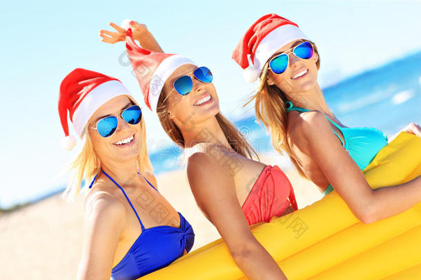 一群戴着圣诞老人帽子的女孩在海滩上玩得很开心