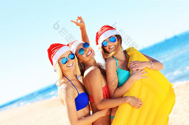 一群戴着圣诞老人帽子的女孩在海滩上玩得很开心