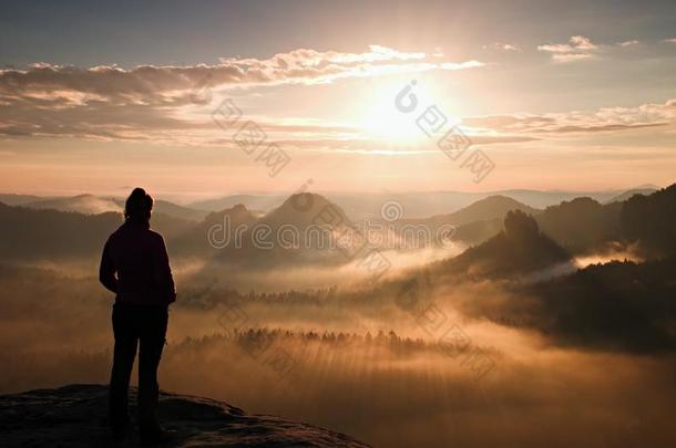 独自的年轻女孩旅游盛宴，秋天的黎明在砂岩岩石的尖角上，看着山谷到太阳。