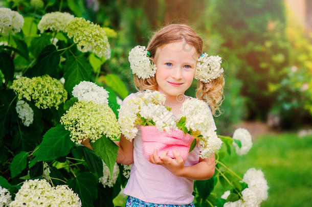 可爱的快乐女孩与绣球花束在夏季花园
