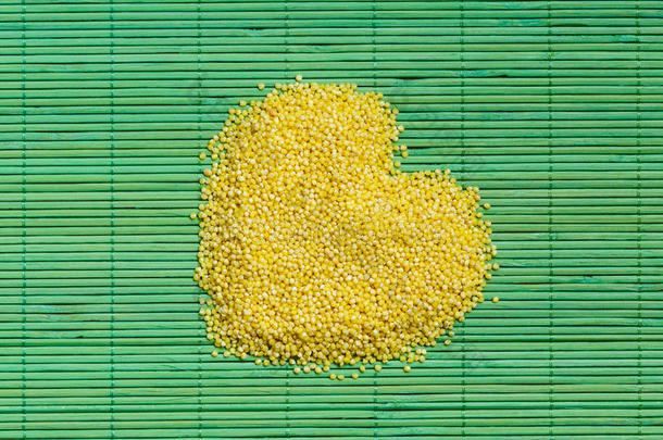 小米在绿色的垫子表面上摇动着心形的小米。