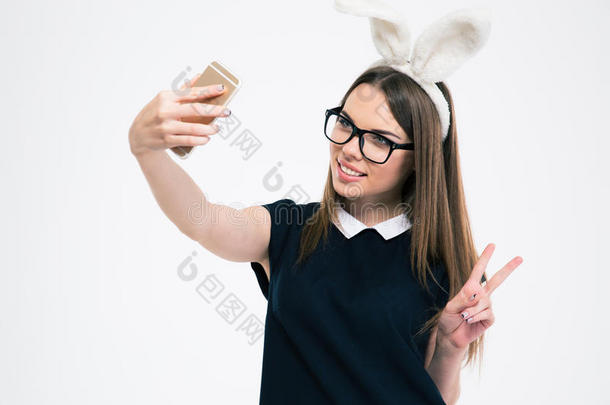 有兔子耳朵的女孩在智能手机上拍自拍照片