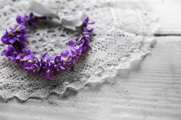 新娘花环躺在花边餐巾上。 邀请卡。 紫罗兰花。