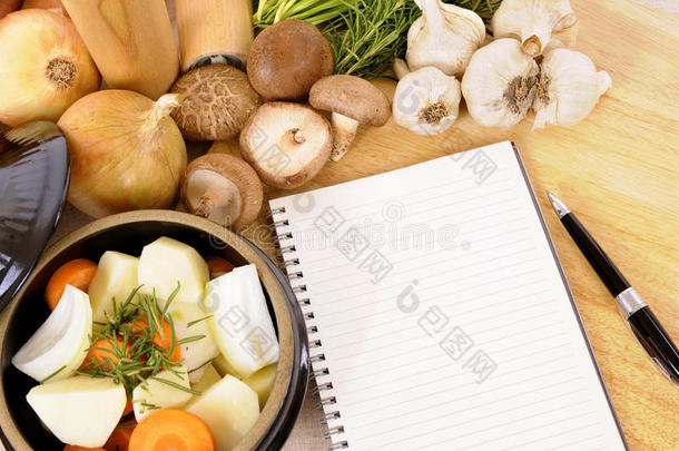 砂锅菜与有机蔬菜和草药在厨房工作台面与食谱或食谱