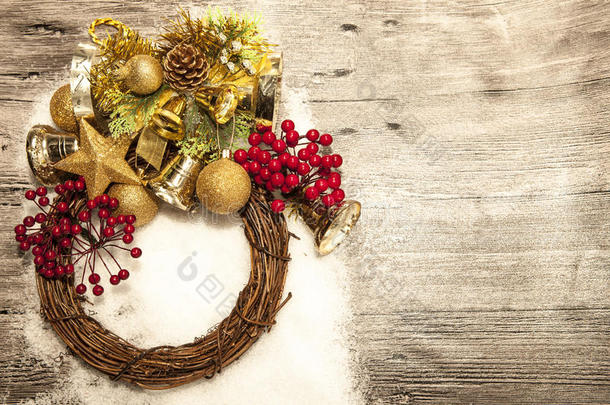 闪闪发光的金色圣诞球，铃铛，花环，和星星在木制背景与雪。
