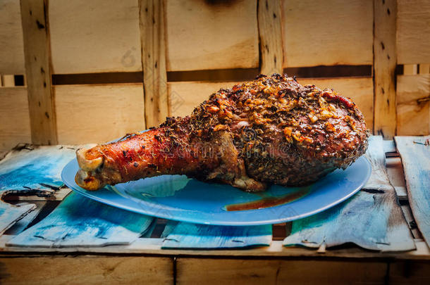 伟大的新鲜烤火鸡腿洒上香料躺在一个蓝色的盘子到黑色的木制背景