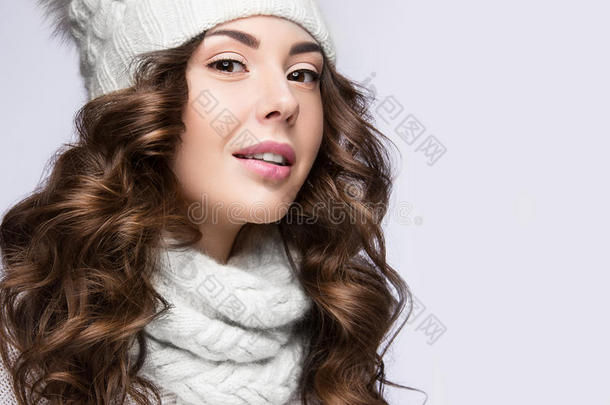 美丽的女孩，温柔的化妆，卷发和微笑的白色针织帽。 温暖的冬天形象。 美丽的脸。