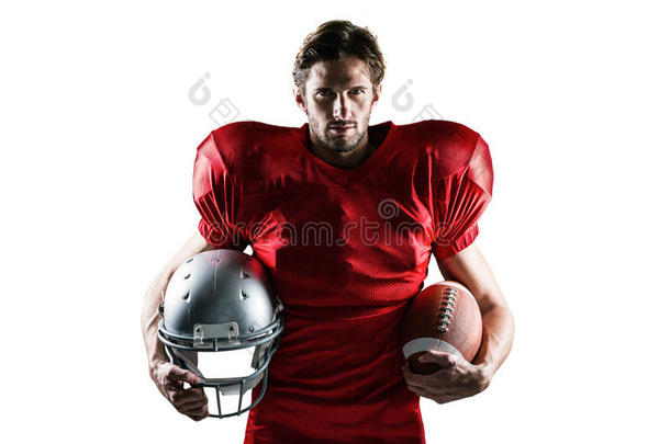 自信的美国足球运动员在红色球衣上拿着头盔和球