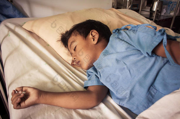 一个小亚洲男孩生病睡<strong>在医院的床上</strong>
