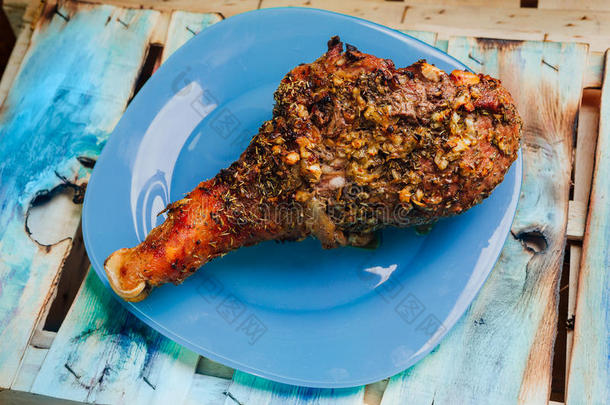 伟大的新鲜烤火鸡腿和切片撒香料躺在一个蓝色的盘子到黑色的木制背景