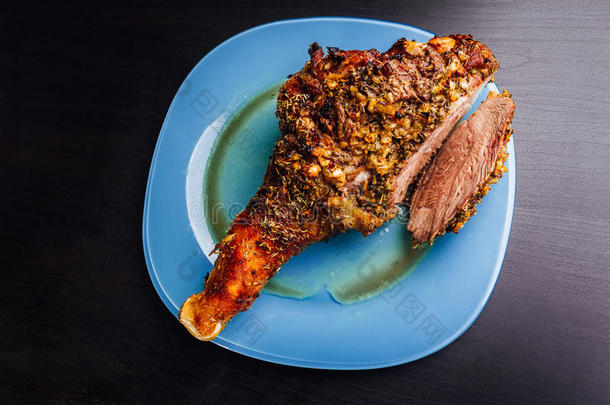 伟大的新鲜烤火鸡腿和切片撒香料躺在一个蓝色的盘子到黑色的木制背景