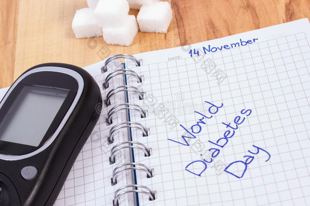 血糖仪，世界糖尿病日写在笔记本和糖立方体