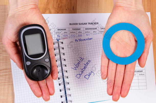 血糖仪和蓝色圆圈在手，象征糖尿病，世界糖尿病日