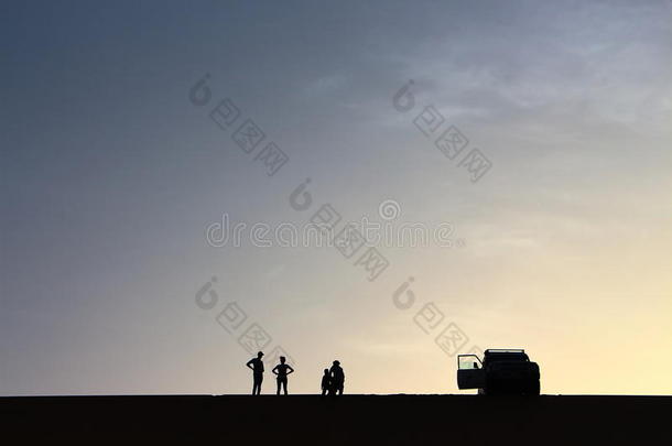 一群冒险者在埃及达赫拉绿洲享受美丽的夏季日落时，从一个大沙丘的顶部敬礼