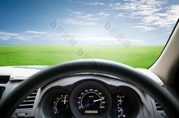 汽车仪表板在绿色的草地和天空上行驶。 汽车驾驶f