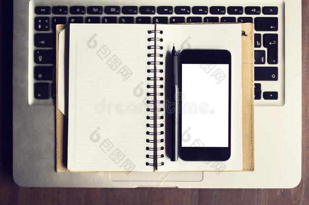 空白智能手机，钢笔和空白日记在键盘上的膝盖