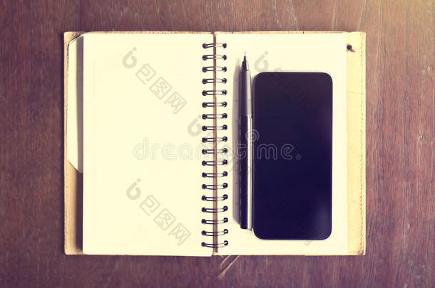 带智能手机的空白日记和木桌上的钢笔