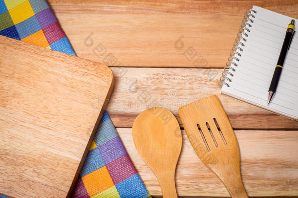木制背景上的叉子、刀、笔记本日记和桌布。 上面
