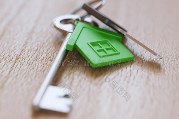绿色房屋钥匙链和钥匙在桌子上特写