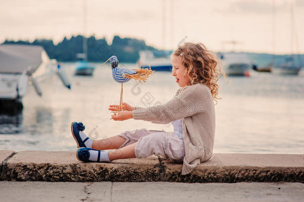 斯洛文尼亚的一个小女孩暑假在海边玩玩具鸟
