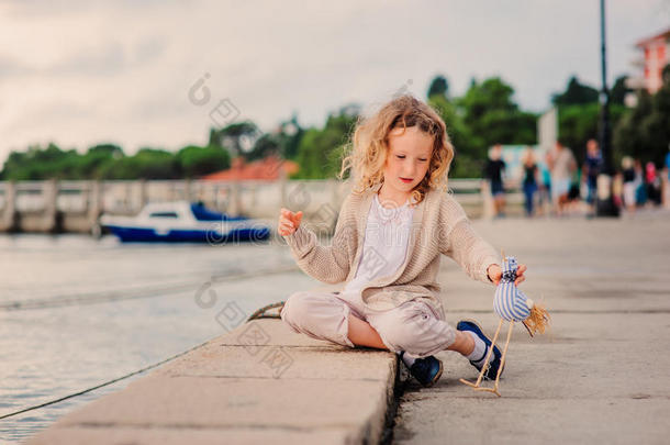 孩子女孩在海边玩玩具鸟暑假，有海洋背景