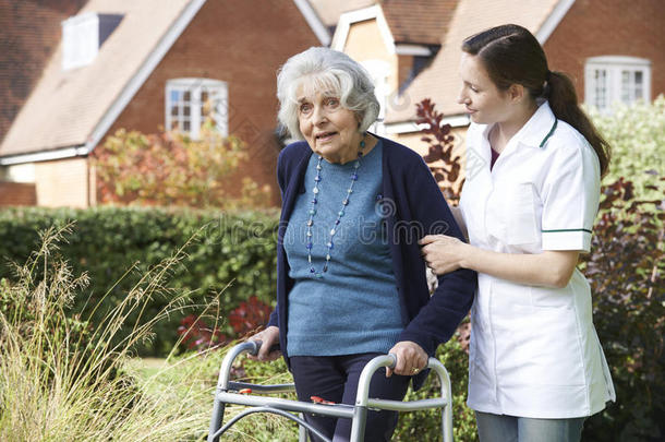 照顾者帮助老人用步行架在花园里散步
