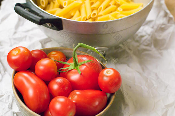近距离观看一个装满意大利意大利面的过滤器和一杯装满西红柿的纸