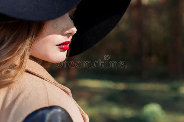 漂亮的女人戴着优雅的黑色帽子，嘴唇上有大片的田野和鲜红的口红