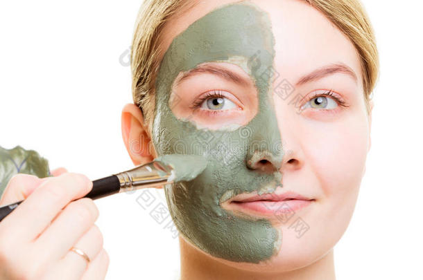 化妆师在女人脸上涂上粘土面膜。