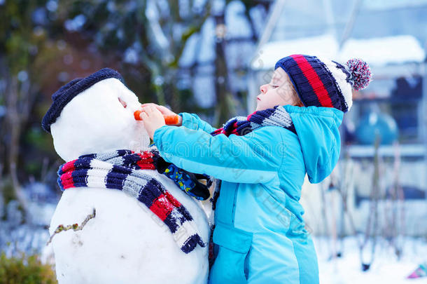 有趣的小男孩在冬天<strong>堆雪人</strong>