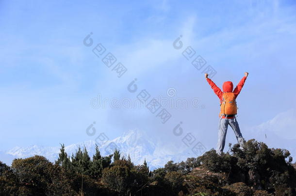 欢呼<strong>的</strong>年轻女子徒步旅行者张开双臂来到美丽<strong>的</strong>雪山