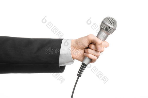 商业和演讲主题：穿黑色西装的人在演播室的一个孤立的白色背景上拿着一个灰色的麦克风
