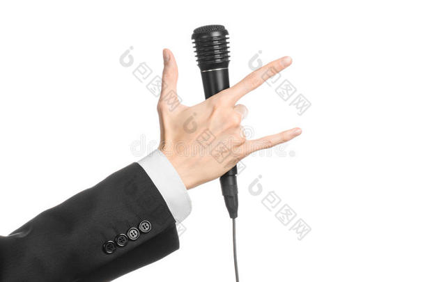 商业与演讲主题：在演播室里，一个身穿黑色西装的男人拿着一个隔离在白色背景上的黑色麦克风