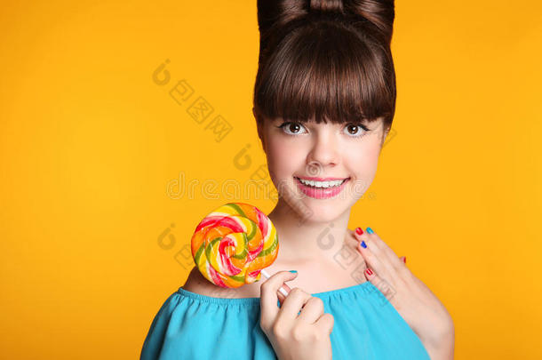 美丽快乐微笑的十几岁女孩吃五颜六色的棒棒糖。 棒棒糖