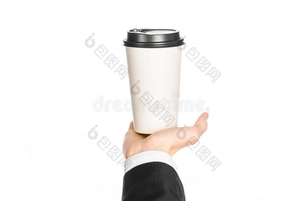 商务午餐咖啡主题：穿黑色西装的商人拿着一杯白色空白纸杯咖啡和一顶棕色塑料帽