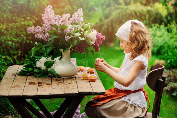 在春天的花园<strong>茶会</strong>上，女孩用鲜花装饰蛋糕