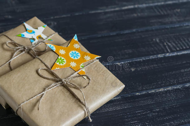 圣诞礼物在牛皮纸上，自制的标签在一个黑暗的木制表面。